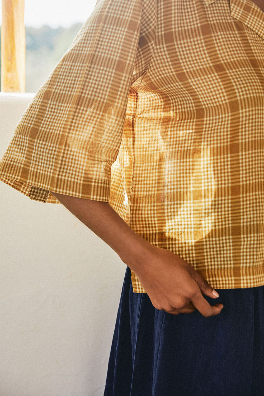 Close-up of the Golden Meadow Shirt sleeve and side seam, showing textured mustard check fabric in natural light.