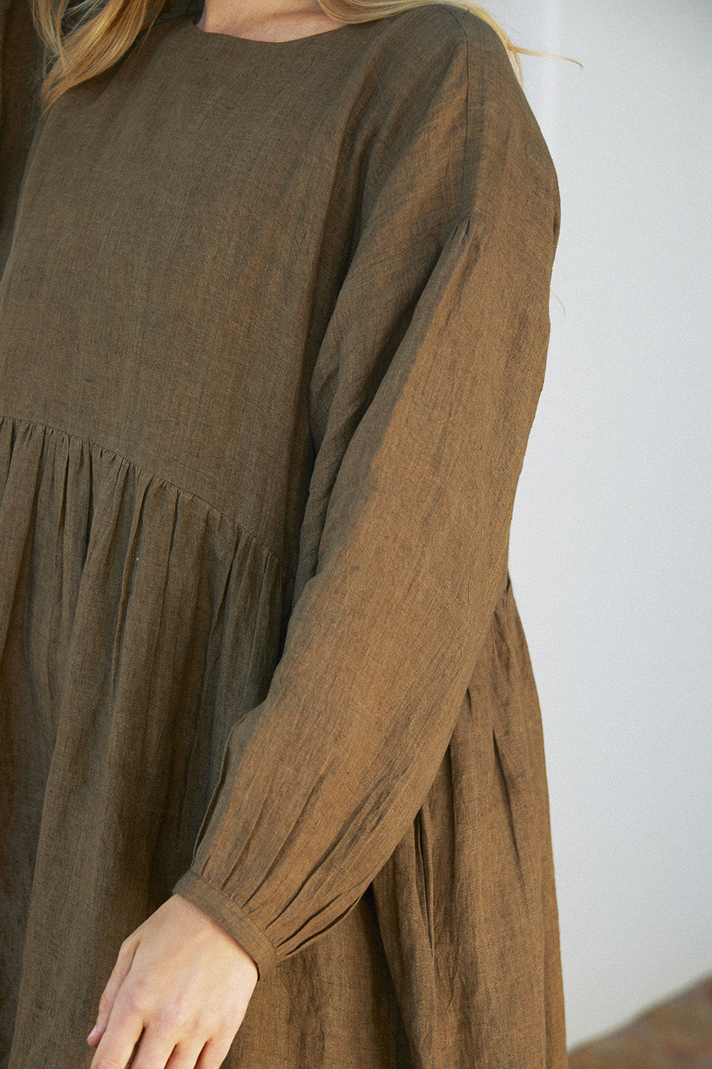 Close-up of the Olive Drift Dress showing gathered waist detailing and full sleeves in earthy olive green fabric.