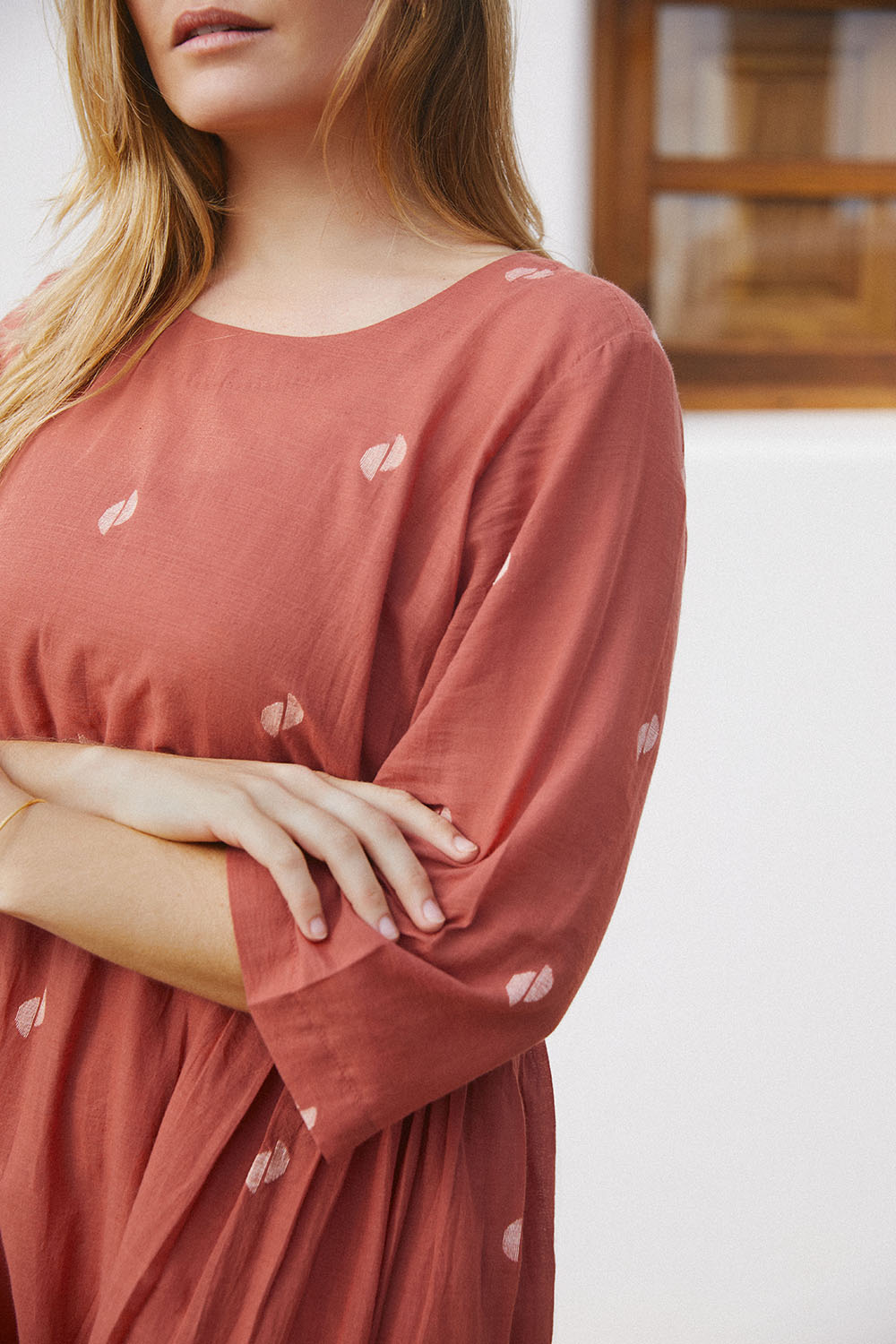 Close-up of rust-colored, long-sleeved, Sienna Moon Side Flared Dress with a round neckline.